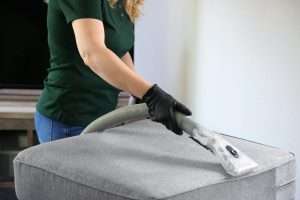 A professional cleaner vacuuming a carpet in a modern living room.