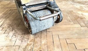 Man sanding a wooden surface with sandpaper in a workshop.